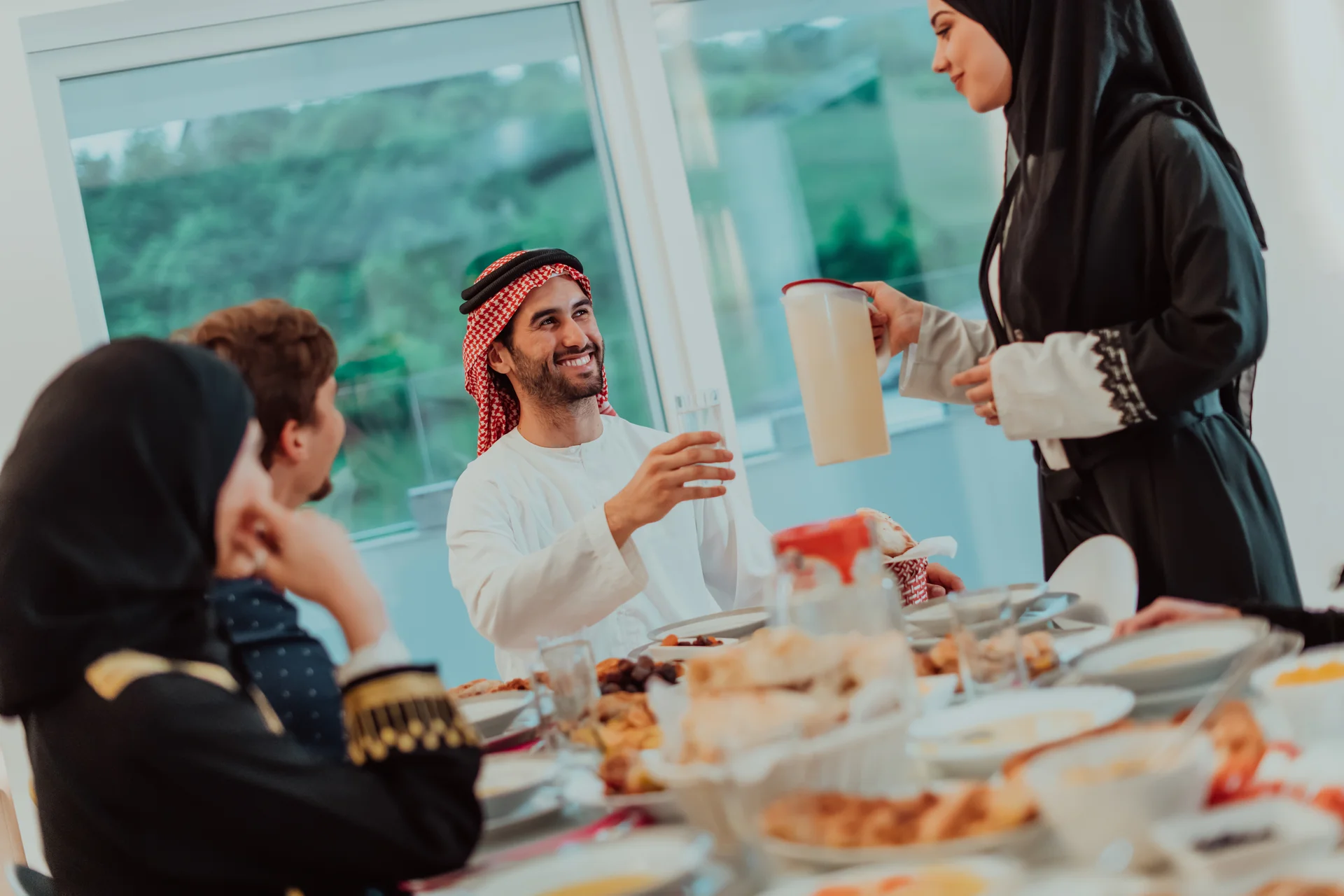 Muslim family having Iftar dinner drinking water to break feast. Eating traditional food during Ramadan feasting month at home. The Islamic Halal Eating and Drinking in modern home.