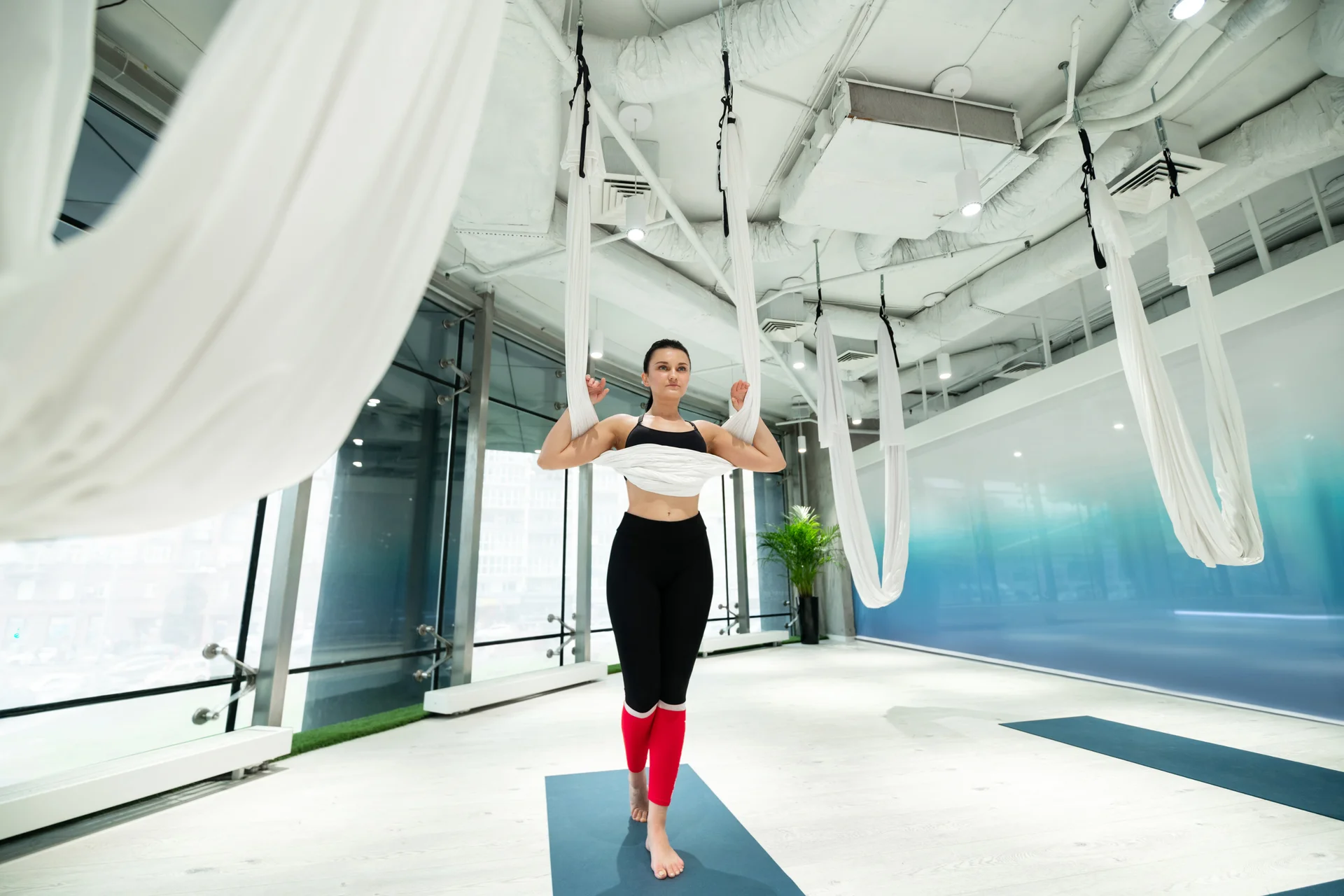 Standing on mat. Slim dark-haired woman standing on mat before practicing aerial yoga