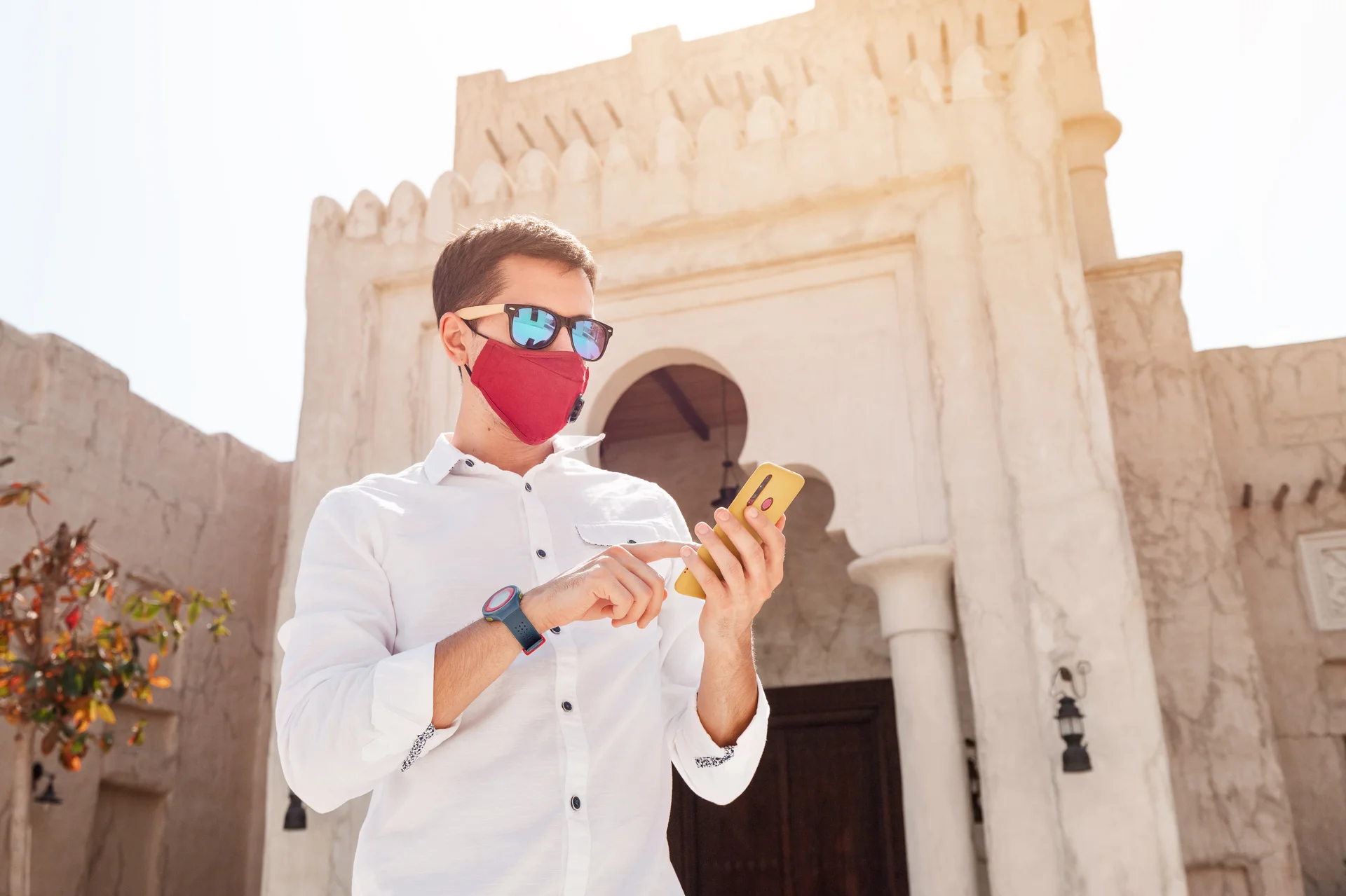 Man wearing a protective medical mask types a message in an app on his smartphone in the old city of Bur Dubai Concert of coronavirus epidemic and covid19