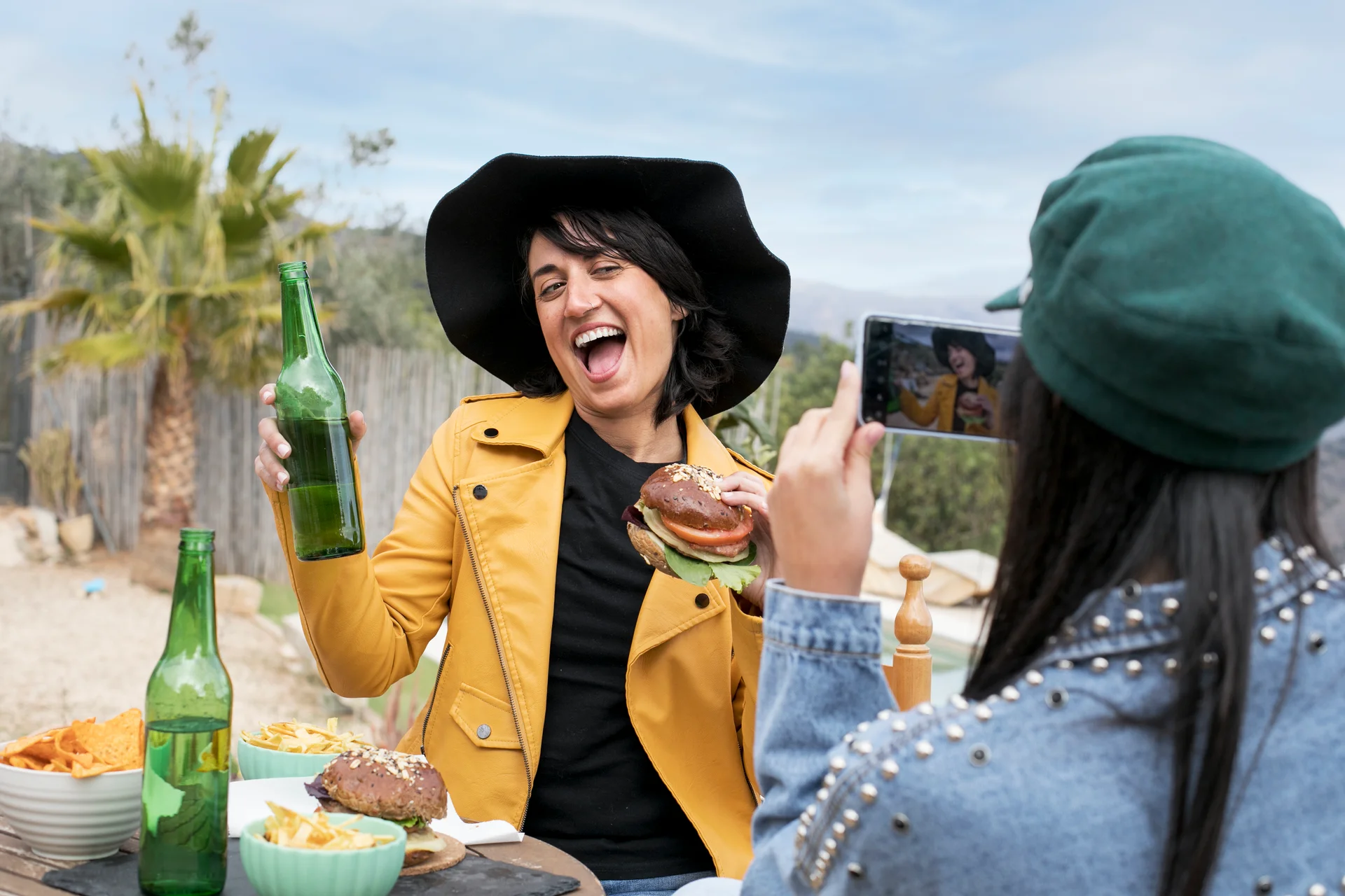 Medium shot friend taking photos of woman with burger