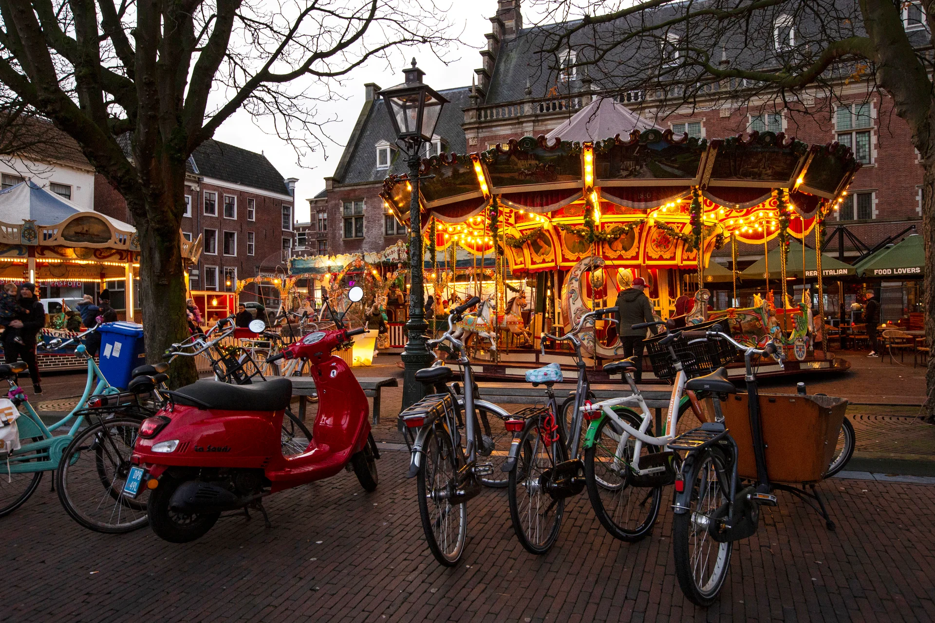 A carousel with a scooter and a bicycles in the foreground