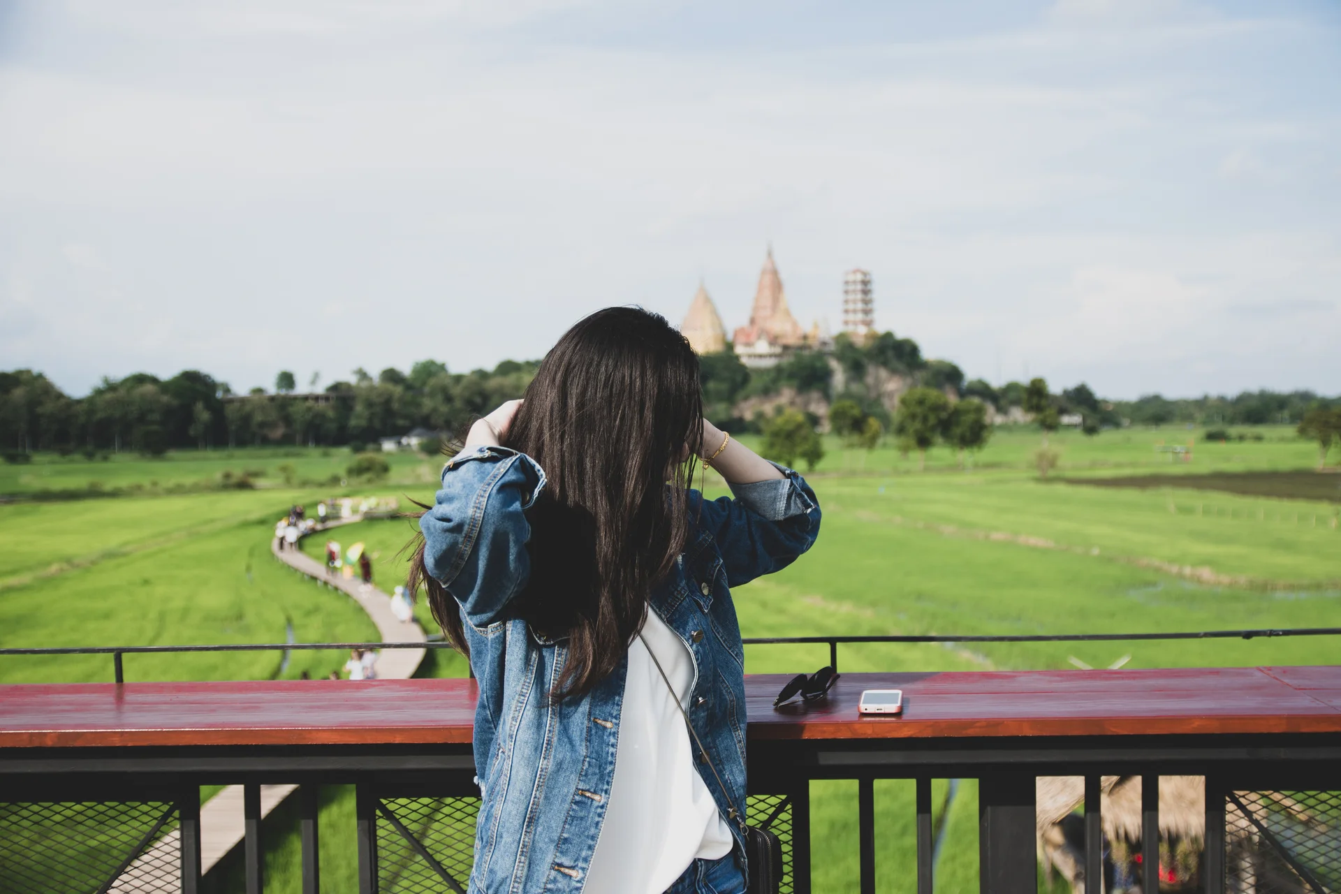 Woman wearing denim jacket standing by railing