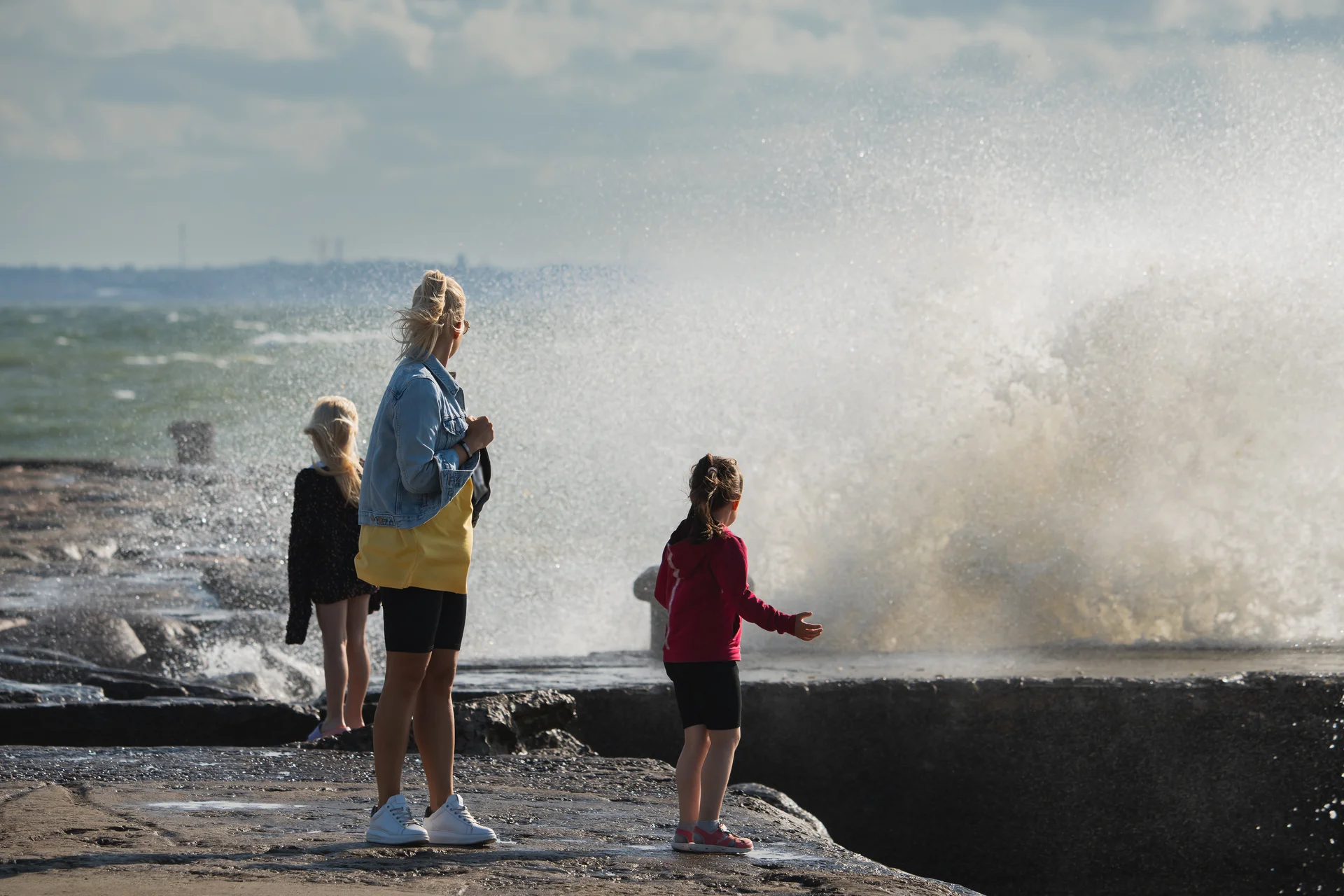 Mom with children on the sea pier in the summer during a storm