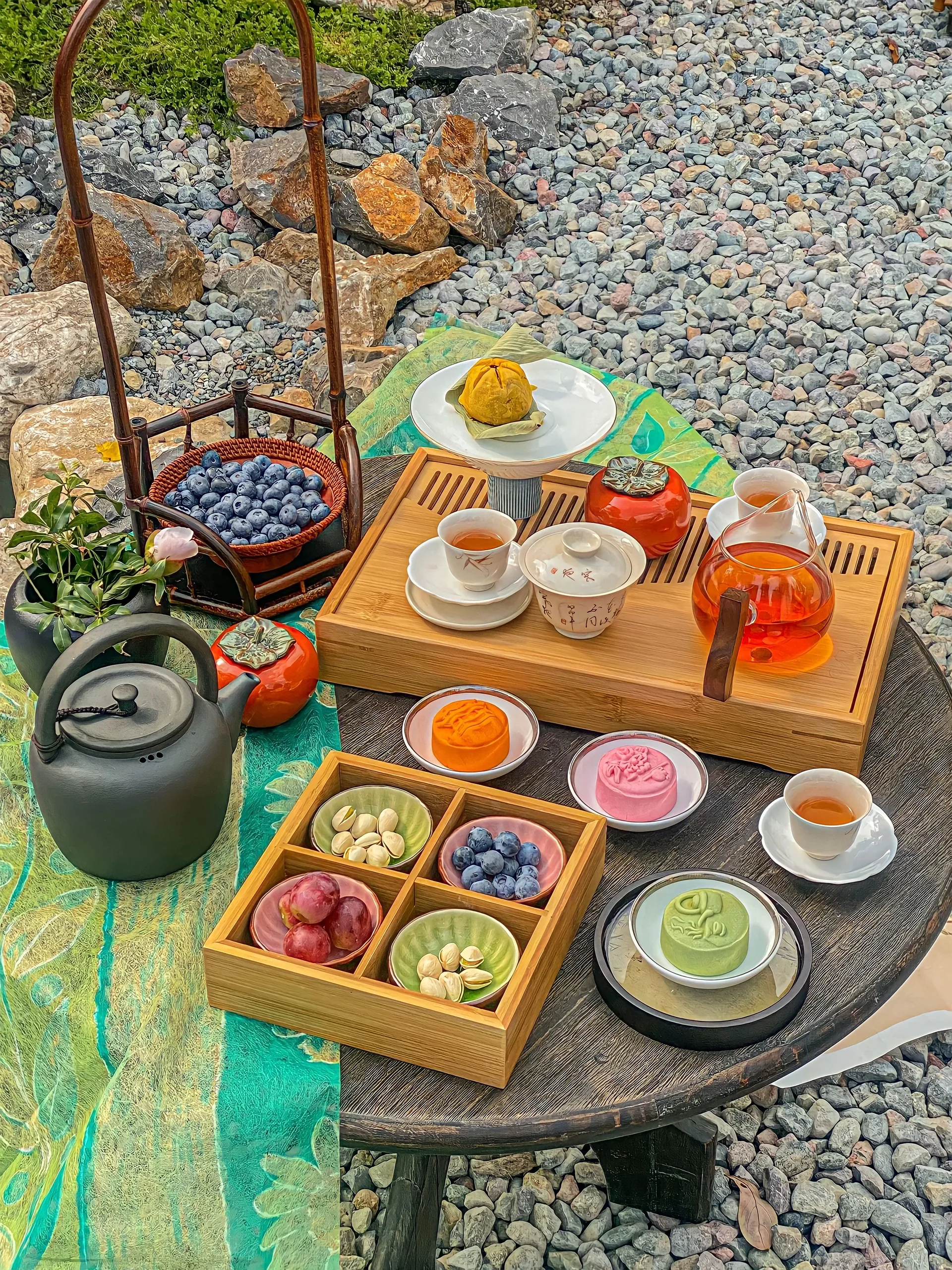 A table with a tea set and a teapot with different foods on it.