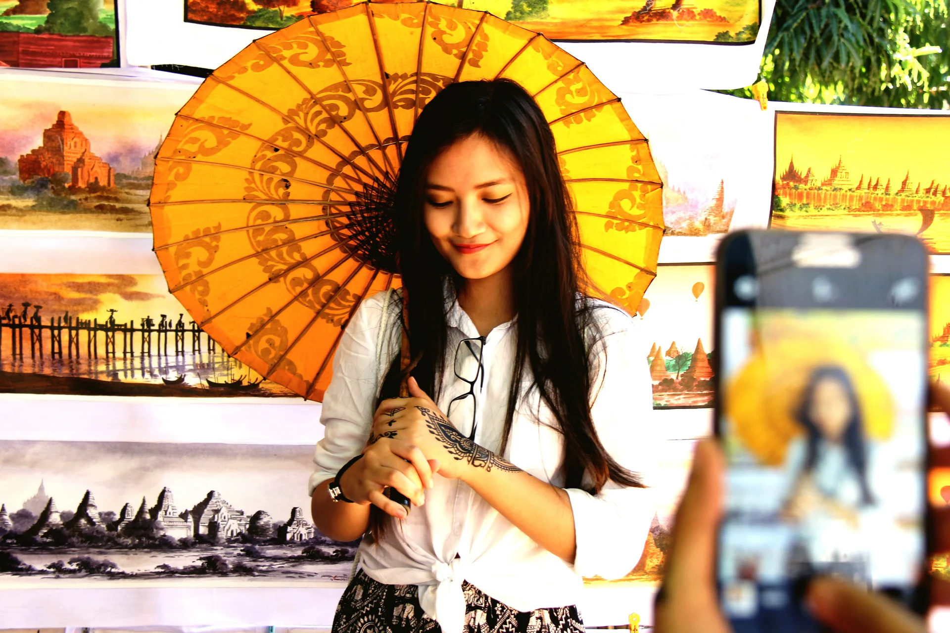 Cropped hands photographing woman holding umbrella