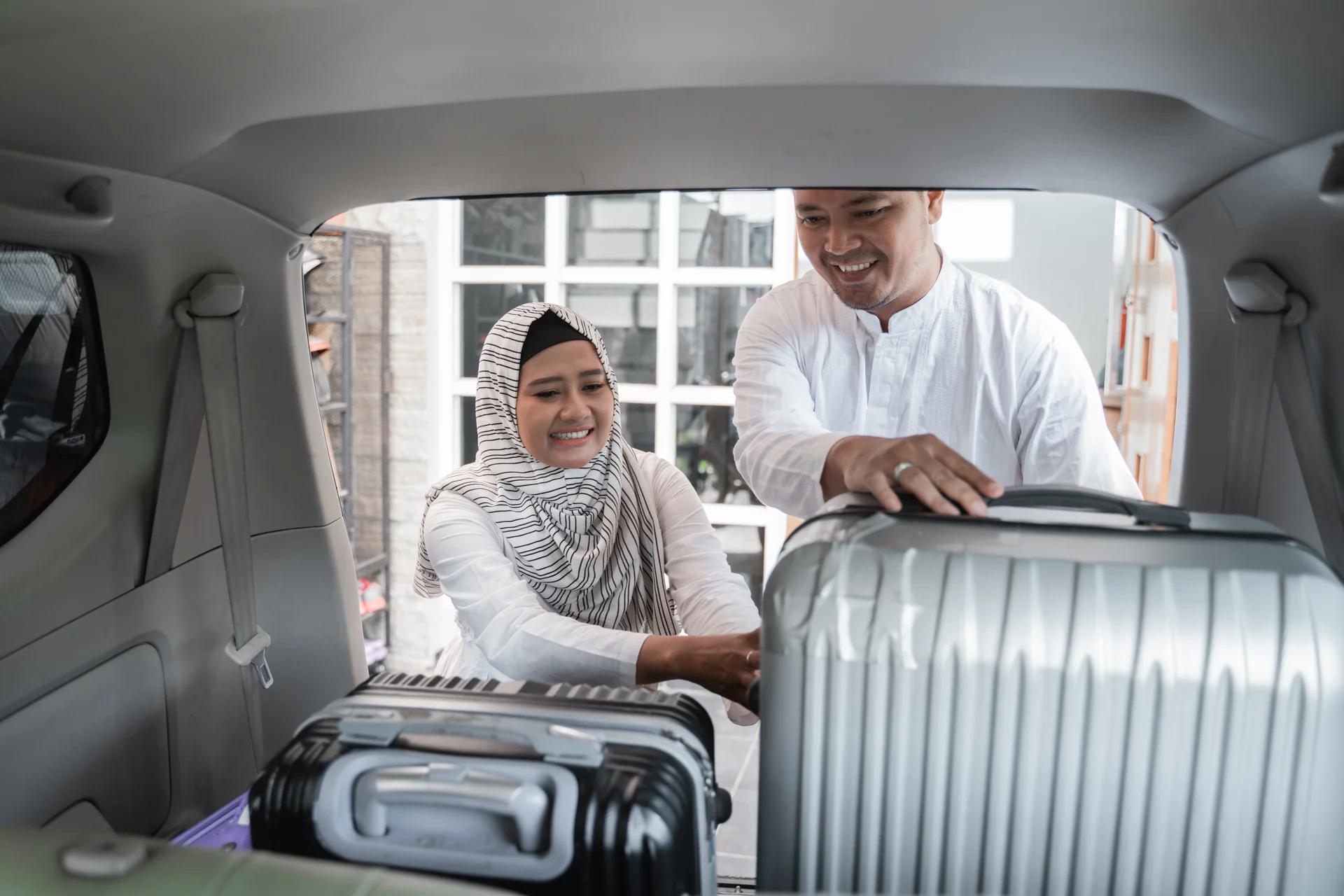 Muslim couple packing suitcase in the car