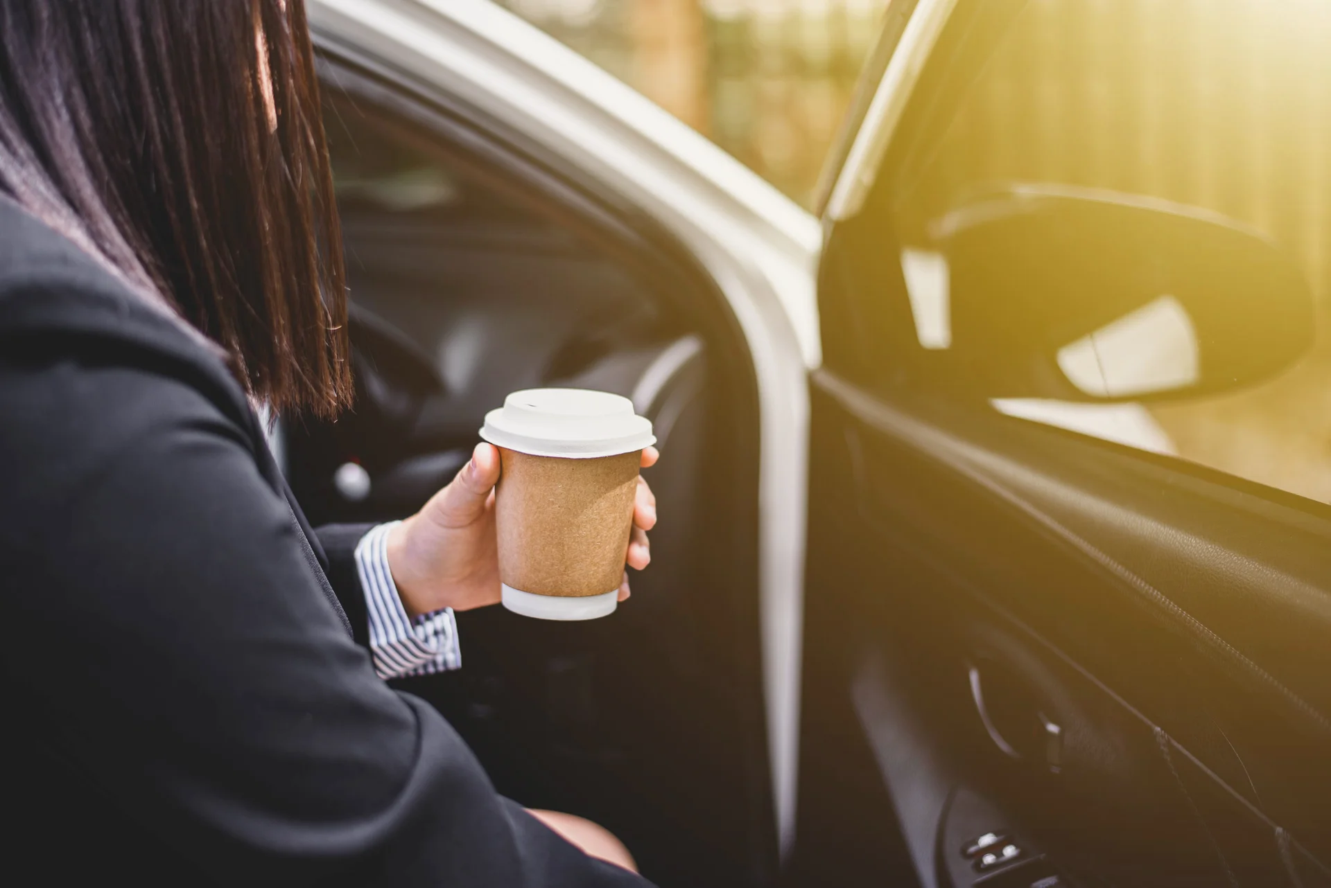 Midsection of woman with coffee cup sitting in car
